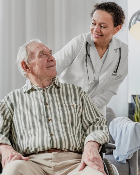 Doctor caring for elderly man in wheelchair at home