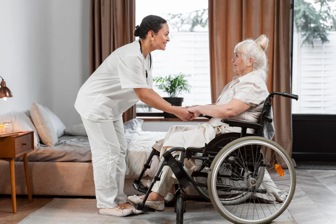 Compassionate caregiver holding hands with elderly woman in wheelchair at home