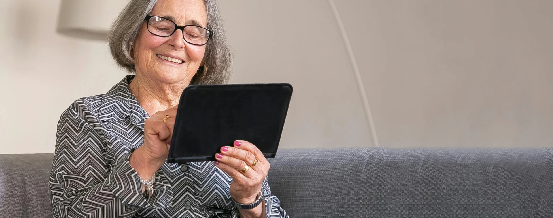 Resident smiling while using tablet independently at home