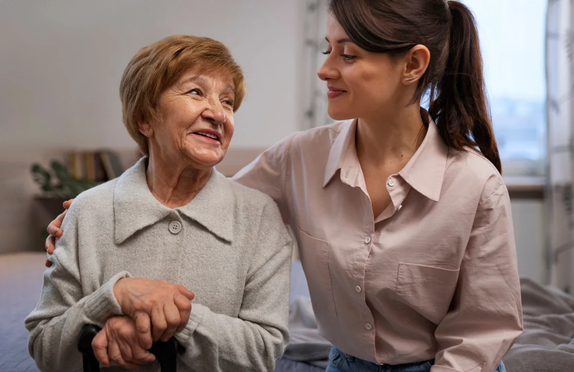 Compassionate caregiver with arm around elderly woman, sharing a warm moment at home
